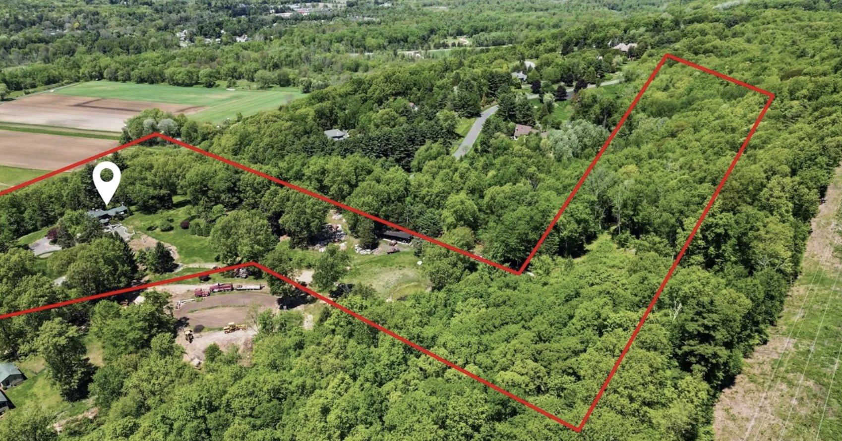 Aerial view of a wooded parcel of about 14.75 acres in Simsbury CT with the boundary outlined in red and open farm fields alongside